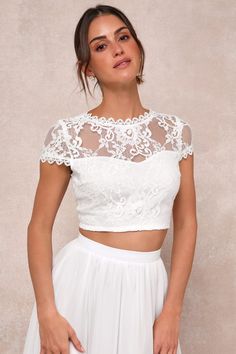 a woman wearing a white crop top and skirt