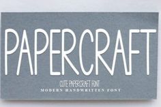 a papercraft business card with the word papercraft written in white ink on a gray background