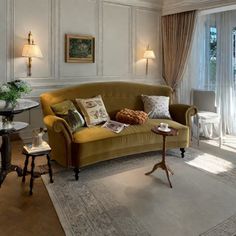 a living room filled with furniture next to a window covered in drapes and curtains