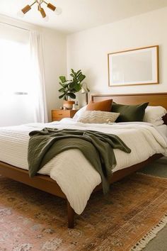 a bedroom with a bed, rugs and plants in the corner on the floor