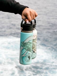 a person is holding a water bottle in their hand while standing on the edge of a boat