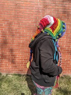 a person with a colorful hat and backpack standing in front of a brick wall