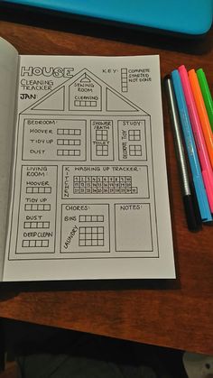 an open book on top of a wooden table next to colored markers and pencils