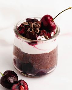 a dessert in a jar with cherries on the side