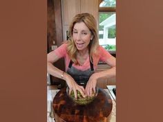 a woman in an apron is preparing food on top of a large bowl with vegetables