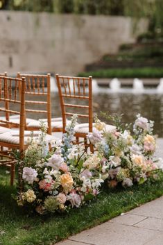 chairs and flowers are lined up on the grass by the water at this wedding ceremony