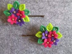 two colorful flower hair pins sitting on top of a gray carpeted floor next to each other