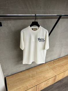 a white t - shirt hanging on a clothes rack