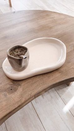 a wooden table with a white plate and bowl on it