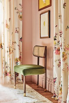 a green chair sitting in front of a window covered in curtains and drapes