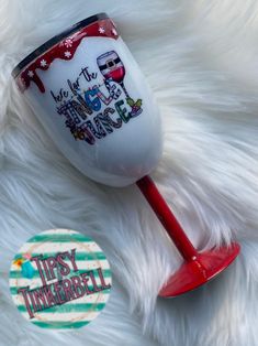 a red wine glass sitting on top of a white fur covered floor next to a sticker