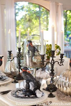 a dining room table is set with candles and glass vases