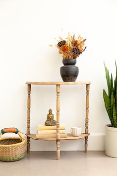 a table with books and a potted plant on it next to a white wall