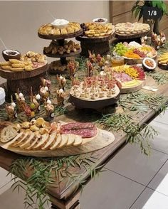 a table topped with lots of food on top of a wooden table covered in greenery