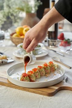 a person dipping sauce on some food on a plate