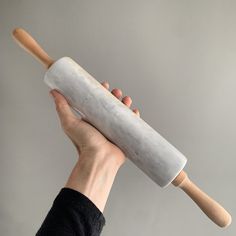 a person holding a rolling pin in their left hand with a wooden handle on it