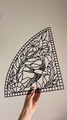 a hand holding up a piece of art that looks like a triangle with flowers on it