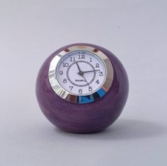 a purple ball shaped clock on a white surface