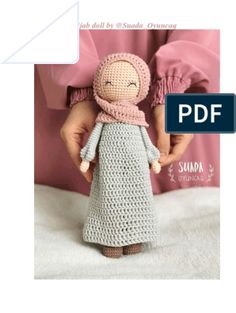 a crocheted doll with a scarf around it's head is held by someone