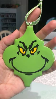 a hand holding a green keychain with an angry grin face on it