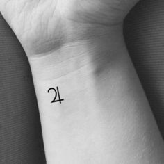 a small wrist tattoo with the number twenty four on it's left side, in black and white