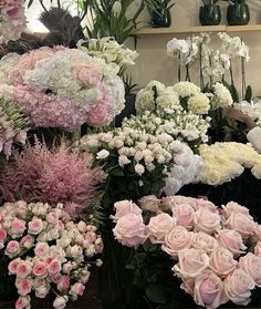 a bunch of flowers that are sitting on the ground in front of some shelves with vases