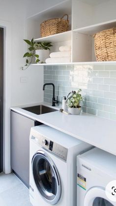 a washer and dryer in a small room with open shelving on the wall