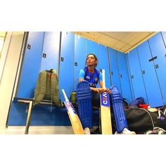 a woman sitting in the locker room with her bat and helmet on, ready to play cricket