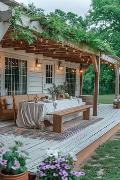 an outdoor dining area with wooden benches and string lights on the roof, surrounded by potted plants