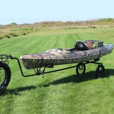 a bike with a kayak on it is parked in the middle of a field