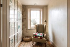 a chair sitting in front of a window next to a wall with pictures on it