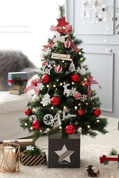 a small christmas tree with ornaments and decorations on it in a living room next to presents