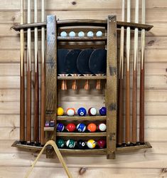 a rack with pool balls and cues in it next to a wall mounted rack