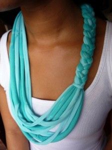 a woman wearing a white tank top and blue necklace with long braids on it