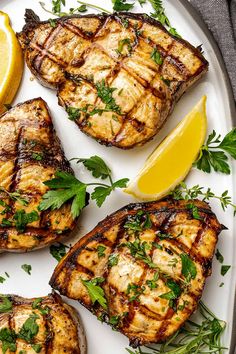 grilled pork chops with lemon and parsley garnish on a white plate