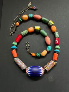 Chevron and Millefiori Venetian beaded Antique Necklace with turquoise, red and orange Coral, Vintage Carnelian, Malachite, Chrysoprase and Amethyst  gemstone beads.   6 layers Chevron bead necklace with Antique Millefiori glass various colors collected from 1930's.  This necklace measures 23" with an extension bronze oval Rolo chain of 4 more inches for a total of 27" in total length.  There is a genuine Amethyst & a bronze leaf accent hanging from the extension chain.   Finished with a Bali br Luxury Vintage Beaded Necklaces With Colorful Beads, Artisan Multicolor Necklaces With Spacer Beads, Eclectic Multicolor Jewelry With Spacer Beads, Eclectic Multicolor Spacer Beads Jewelry, Vibrant Necklace With Large Round Beads, Antique Multicolor Beaded Necklaces, Traditional Multicolor Gemstone Beads, Bohemian Multicolor Polished Beads And Cabochons, Traditional Turquoise Multi-strand Beaded Necklace