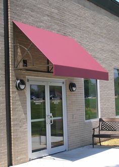 a pink awning on the side of a building next to a bench and door