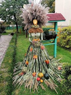 a woman's dress made out of plants and fruits on display in a garden