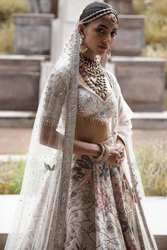 The vintage udaibagh lehenga showcases nature-inspired motifs on an off-white raw silk base, stealing the spotlight with multi-coloured resham aari, tarnished dori work, and intricate hand embroidery using nakshi, dabka, sequins, mirrors, and zardozi. This modern masterpiece is elegantly paired with a net dupatta and veil, adding a touch of timeless grace to your ensemble. Off White Lehenga, Cut Work Blouse, Lehenga And Blouse, White Lehenga, Raw Silk Lehenga, Bridal Lehenga Red, Lehenga Blouse, Designer Jumpsuits, Net Dupatta