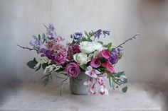 a vase filled with lots of purple and white flowers