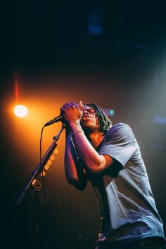 a man with dreadlocks on his head singing into a microphone at a concert