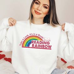 Reading Rainbow Sweatshirt, Rainbow School Crewneck, Bookworm Sweatshirt, Librarian Shirt, Teacher Appreciation, Book Lover Gift, Book Shirt It will become your new favorite Sweatshirt. 👉HOW TO ORDER�👈 1️⃣  Choose your T-shirt color 2️⃣  Choose your T-Shirt size 3️⃣  Choose your design & text color 4️⃣ Need more Items? Add the current item in the cart. And If you like to add more items to your order please press the back button and repeat steps 1-3 again. 5️⃣Once all your desired items are in y White Bookish Sweatshirt With Letter Print, Bookworm Sweatshirt, Rainbow Sweatshirt, Book Shirt, Librarian Shirt, Reading Rainbow, Gifts For Librarians, Design Text, Book Shirts