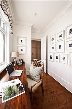 a laptop computer sitting on top of a wooden desk next to a window covered in pictures