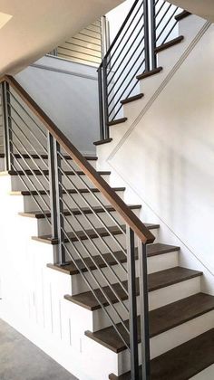 a stair case with wooden steps and metal railings in a room that is painted white