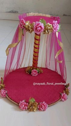 a pink and gold bed with flowers on the bottom is sitting in front of a white wall