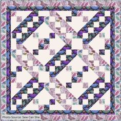 a quilt made with squares and flowers on the front, in shades of pink, blue, green and purple