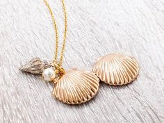 "A lovely and beautiful gold seashell locket necklace. It features a shining gold seashell along with white conch and pearl. The pearl is genuine Swarovski 6mm pearl. It suspends in a gold finished brass chain along with lobster claw clasp closure. The shell locket inside can hold pictures in both side 16mm x 14mm. It is a wonderful idea for gift giving or as a little treat for yourself. Your necklace will present in a gift box and tied with ribbon. Measurements and details: Length: 16\", 18\", Seashell Locket, Melody Mermaid, Shell Locket, Prom Hair Accessories, Gold Locket Necklace, Hair Accessories Gift, Wedding Keepsakes, Shell Pendant, Locket Necklace