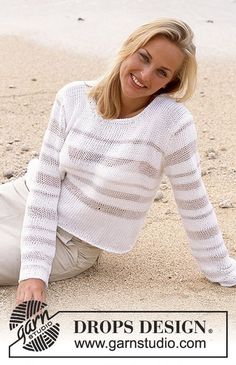 a beautiful blond woman laying on the sand with her legs crossed and smiling at the camera