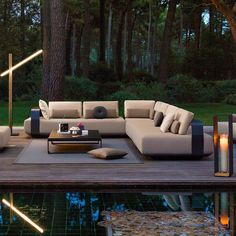 a couch sitting on top of a wooden floor next to a pool in a forest