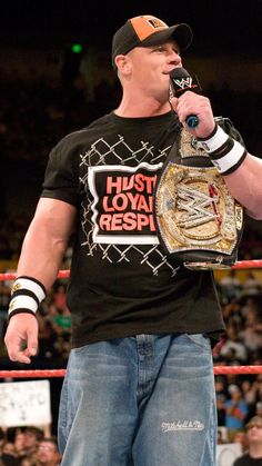 a man in a black shirt and hat holding a wrestling belt with his mouth open